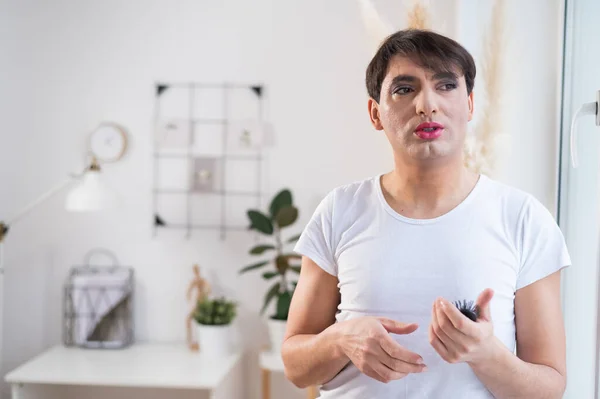 The man is wearing makeup. Transgender posing in the studio