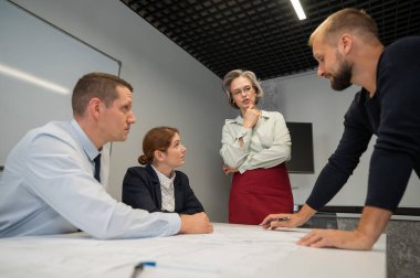 The female boss evaluates the work of subordinates. Designers engineers at a meeting