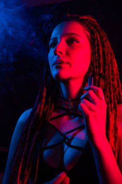 Rastalı beyaz kız kırmızı ışıkta sigara içiyor.