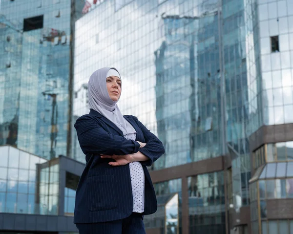Portrait of a pregnant business woman in a hijab and a suit with crossed arms on her chest outdoors