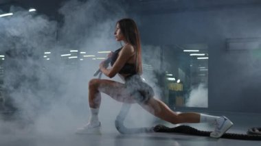 Beyaz kadın ipleri tutuyor ve egzersiz makinesine atlıyor.