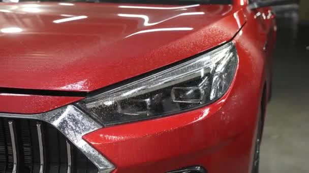一个人用刮胡刀擦洗一辆红色汽车的前灯 — 图库视频影像
