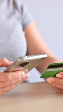 Kadının biri kredi kartıyla akıllı telefondan online alışveriş yapıyor. Dikey video