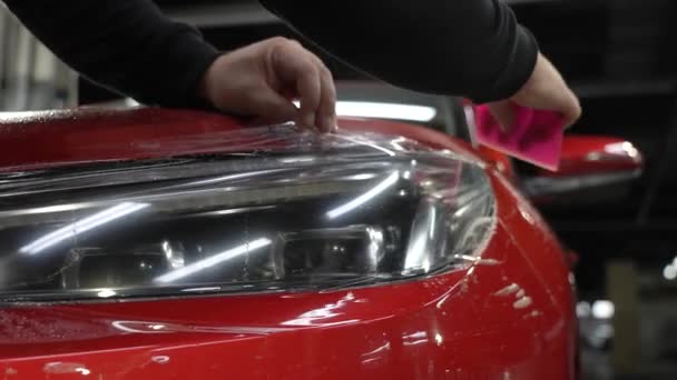 Master Applies Vinyl Film Headlight Red Car Closeup View Worker — Stock Video
