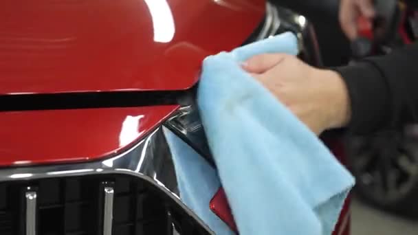Een Man Veegt Koplampen Van Een Rode Auto Met Een — Stockvideo