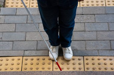 Kadın ayağına, bastona ve dokunsal fayanslara yakın çekim