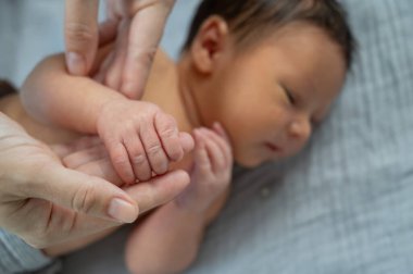 Yeni doğmuş bir çocuk annesinin parmağını tutar. Ellerin yakın çekimi