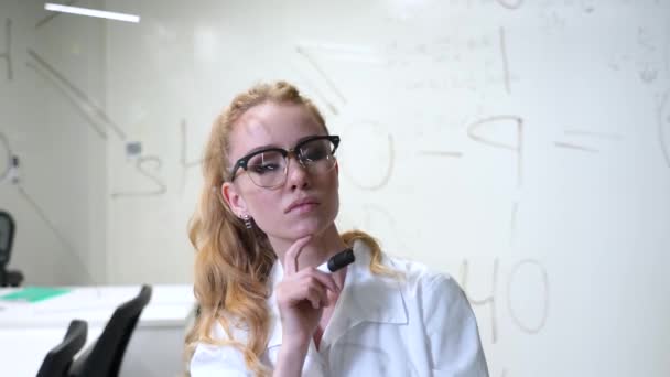 Uma Mulher Caucasiana Vestido Médico Pensa Finaliza Fórmulas Uma Parede — Vídeo de Stock