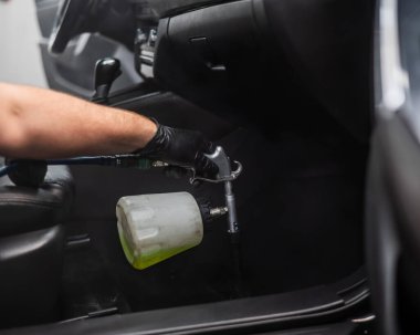 Bir adam arabanın içini profesyonel olarak temizler.