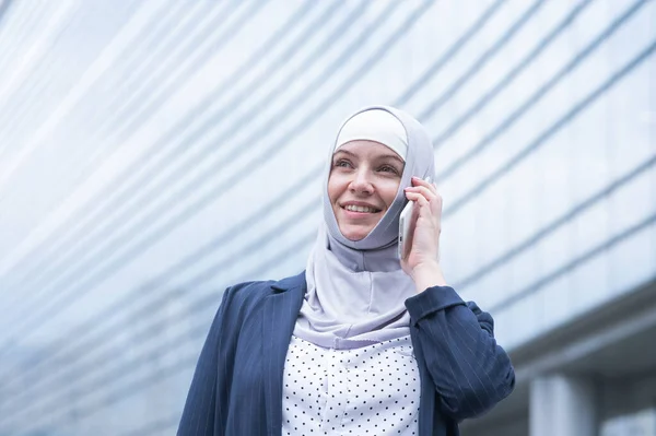 Business woman in hijab and suit talking on smartphone