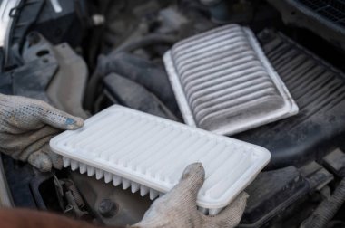 Araba motorundaki hava filtresini değiştiriyor.