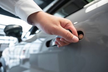 Adamın biri parmak iziyle arabanın kapısını açıyor. Bütünleşik kulp