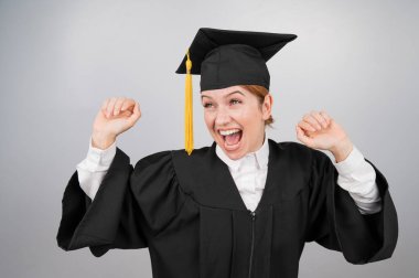 Beyaz arka planda mezuniyet elbisesiyle dans eden beyaz kadın.