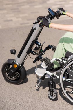 Tekerlekli sandalyeyi özel bir elle kontrol eden bir kadın. Elektrikli bir motosikleti kapat.