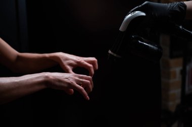 Usta kadınların ellerine boyama boyası sürüyor. Anında bronzlaşma prosedürü.