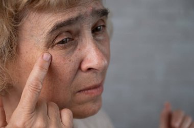 Gözlerindeki kırışıklığı gösteren yaşlı bir kadının yakın plan portresi.