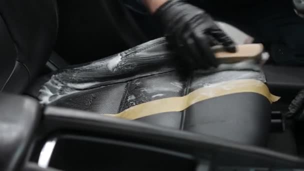 ブラシとクリーニングフォームでブラックレザーカーシートをクリーニングする男 — ストック動画
