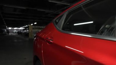Kamera, araba galerisindeki kırmızı bir arabanın üzerinde süzülüyor.
