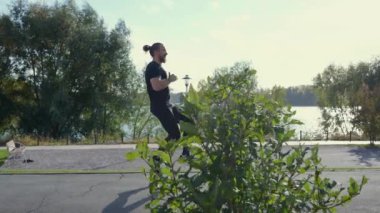 Sakallı adam spor sahasında dizleri yukarıda koşar. Yavaş çekim