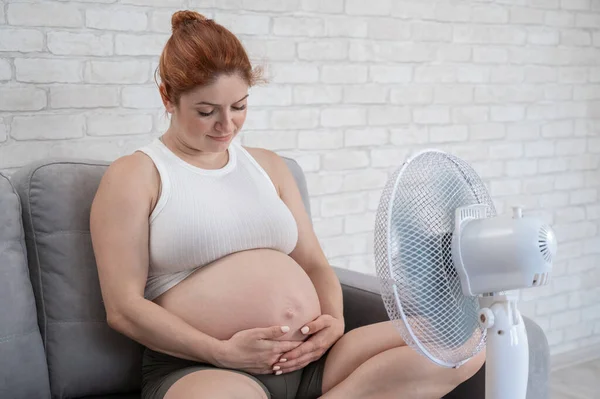 Una Mujer Embarazada Está Sentada Sofá Acariciando Barriga Disfrutando Del — Foto de Stock