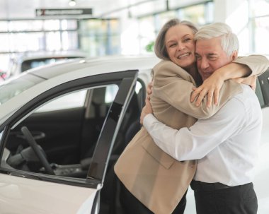 Olgun, beyaz bir çift sarılıyor. Yaşlı adam ve kadın yeni bir araba satın alıyorlar.
