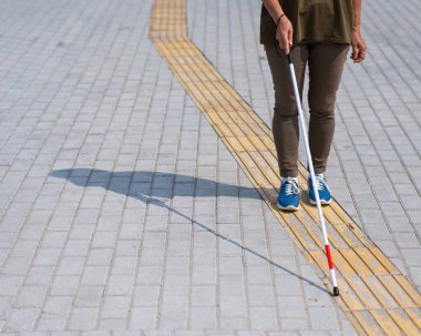 Yaşlı, kör, bastonlu, dokunmatik bir kadının bacaklarına yakın çekim.