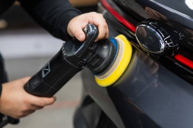 Bir tamirci araba bagajının kapısının yüzeyini öğütme makinesiyle parlatır.