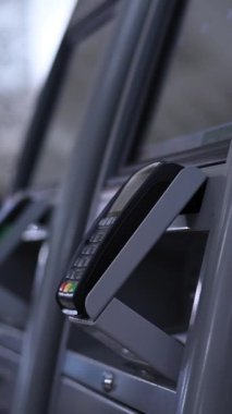 Bir kadın self-servis kasasını kullanır ve bilet parasını akıllı telefonuyla öder. Dikey video