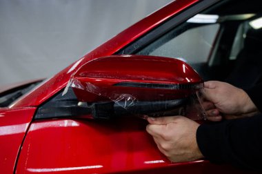 Usta bir arabanın dikiz aynasına vinil film uyguluyor.