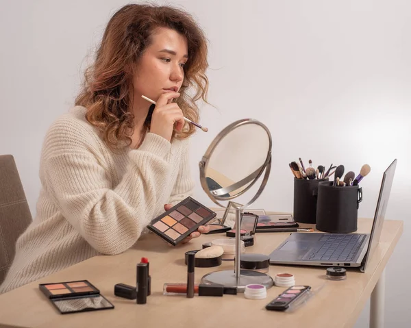 Online training for make-up. A woman teacher explains the makeup application scheme on the air.