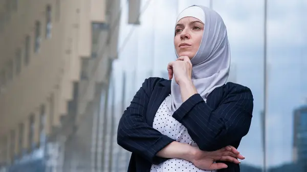 Portrait of pensive business woman in hijab and suit outdoors
