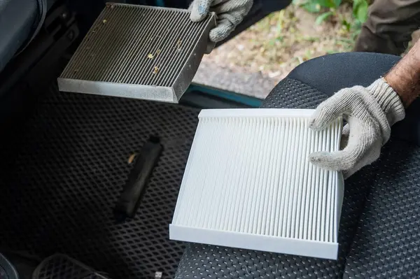 Usta arabanın kabin hava filtresini değiştiriyor.