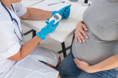 Doktor hamile bir hastanın kan şekerini ölçüyor. Gebelik Diyabet