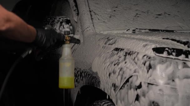 男性は洗車中の黒い車に発泡する スローモーション — ストック動画