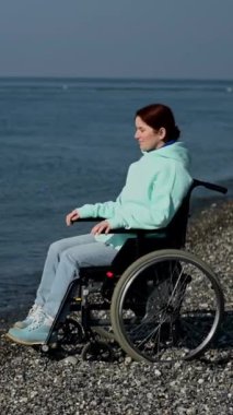 Deniz kıyısında tekerlekli sandalyedeki Kafkasyalı kadın.