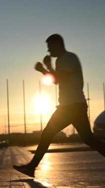 Gün batımında boks antrenmanı yapan bir adam. Dikey video
