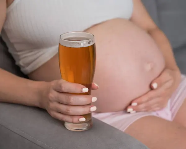 Close Barriga Uma Mulher Grávida Segurando Copo Cerveja Enquanto Senta — Fotografia de Stock