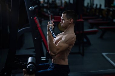 A man does a chest pulldown in the gym