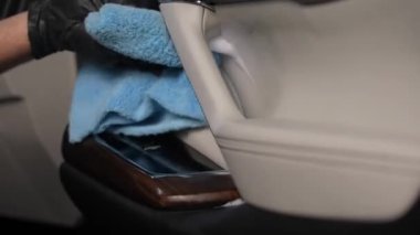 Bir adam arabanın içini mikrofiber bir bezle siliyor.