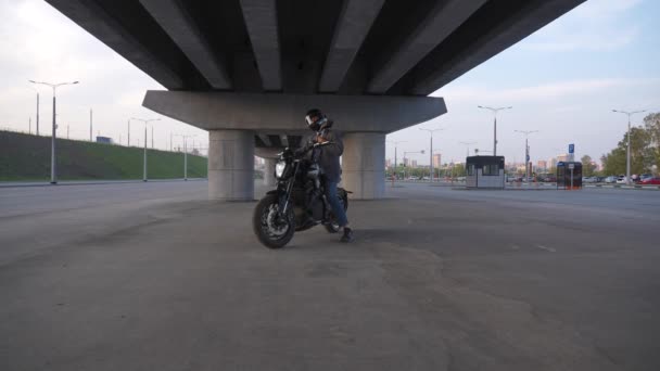 Homem Casaco Capacete Senta Numa Moto Eléctrica Debaixo Uma Ponte — Vídeo de Stock