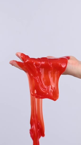 白い背景に女性の手から流れる赤いスライム バーティカルビデオ — ストック動画