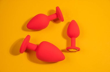 Three size silicone red butt plugs on an orange background