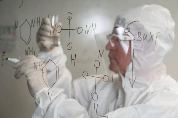 Elderly Caucasian Male Chemist Protective Suit Looks Test Tube Writes — Stock Photo, Image