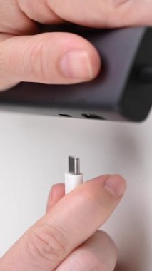 Bir kadın C tipi bir sokete kablo yerleştiriyor. Dikey video