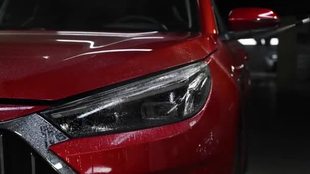 Bir Adam Kırmızı Bir Arabanın Farlarını Kazıyıcı Ile Yıkıyor — Stok video