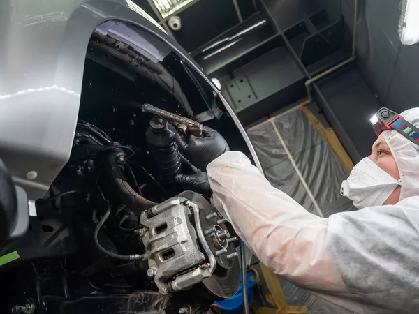汽车机修工将防腐蚀胶乳涂在汽车底座上 — 图库照片