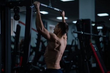 A man does a chest pulldown in the gym
