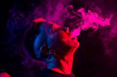 Tıraşlı şakakları olan Asyalı bir kadın neon ışıkta sigara içiyor.