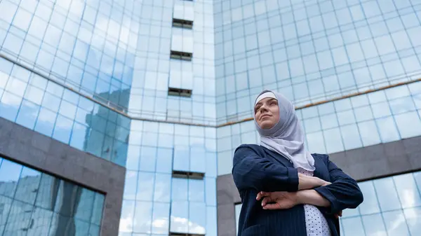 Portrait of a pregnant business woman in a hijab and a suit with crossed arms on her chest outdoors