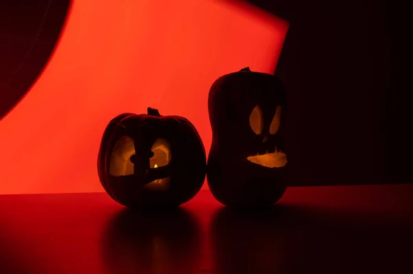 Two jack-o-lanterns glow in the dark on a red background. Halloween decoration